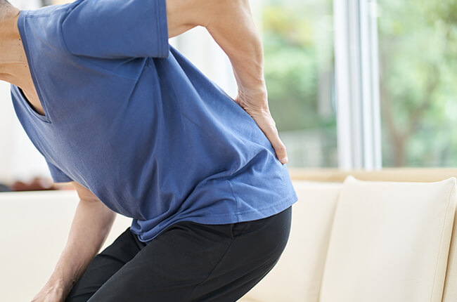 痛みで腰を押さえる男性