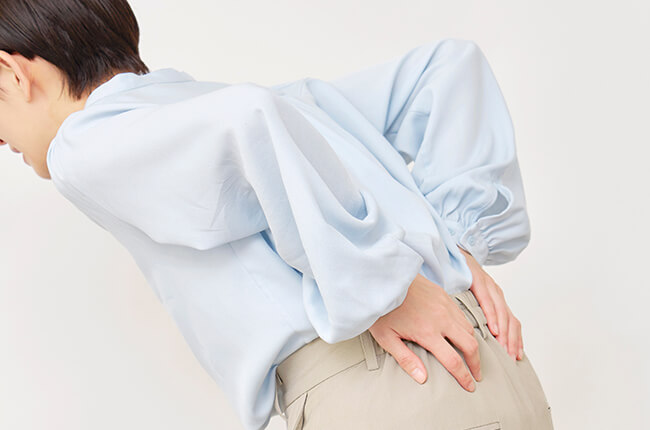 痛みで腰を押さえる女性